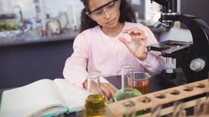 Día internacional de la mujer y la niña en la ciencia: Niña trabajando con instrumentos de laboratorio (probetas, microscópio, libro de notas, etc.).